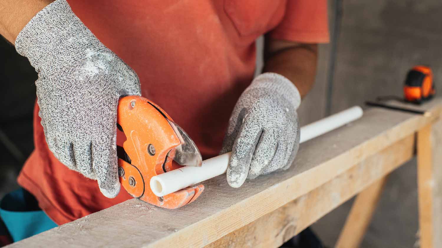 A person cutting a small PVC pipe