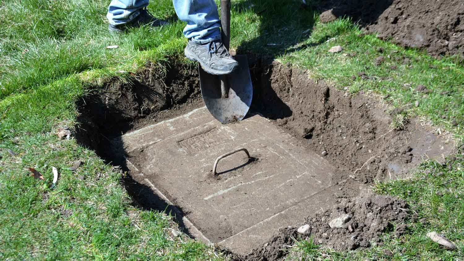 A person digging to find the septic tank system