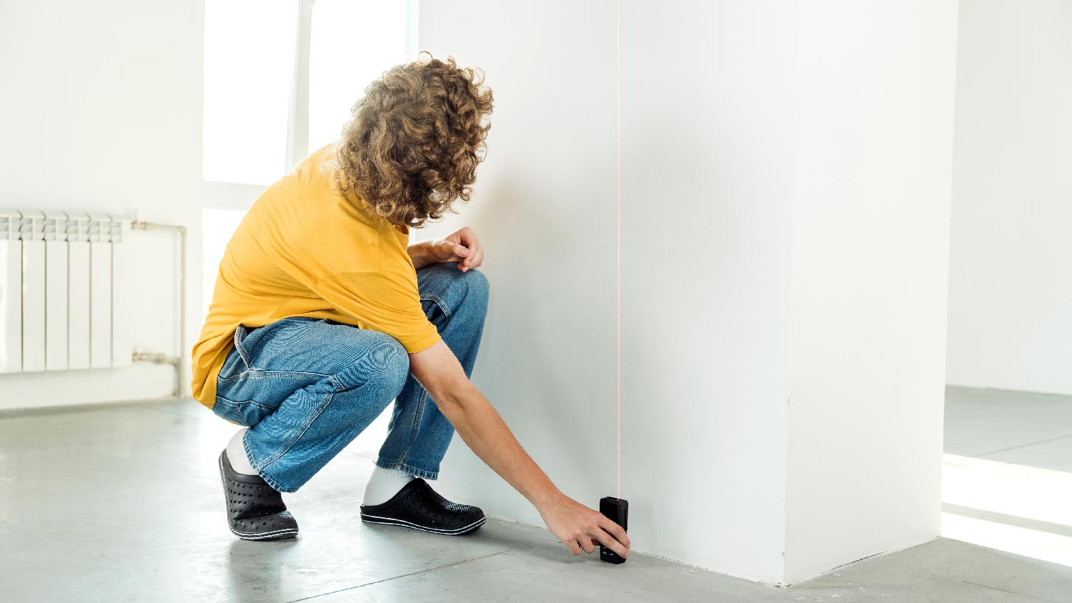 A person measuring the ceiling with a digital measuring tape