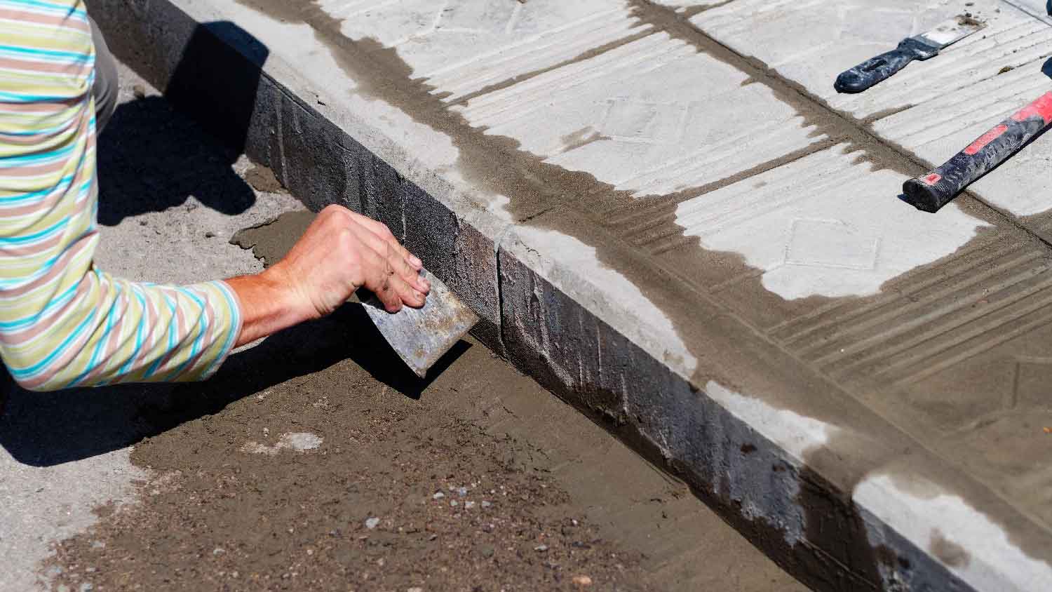 A person finalizing a sidewalk repair