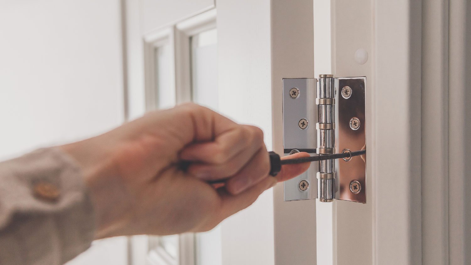 A person fixing the hinges of an interior door