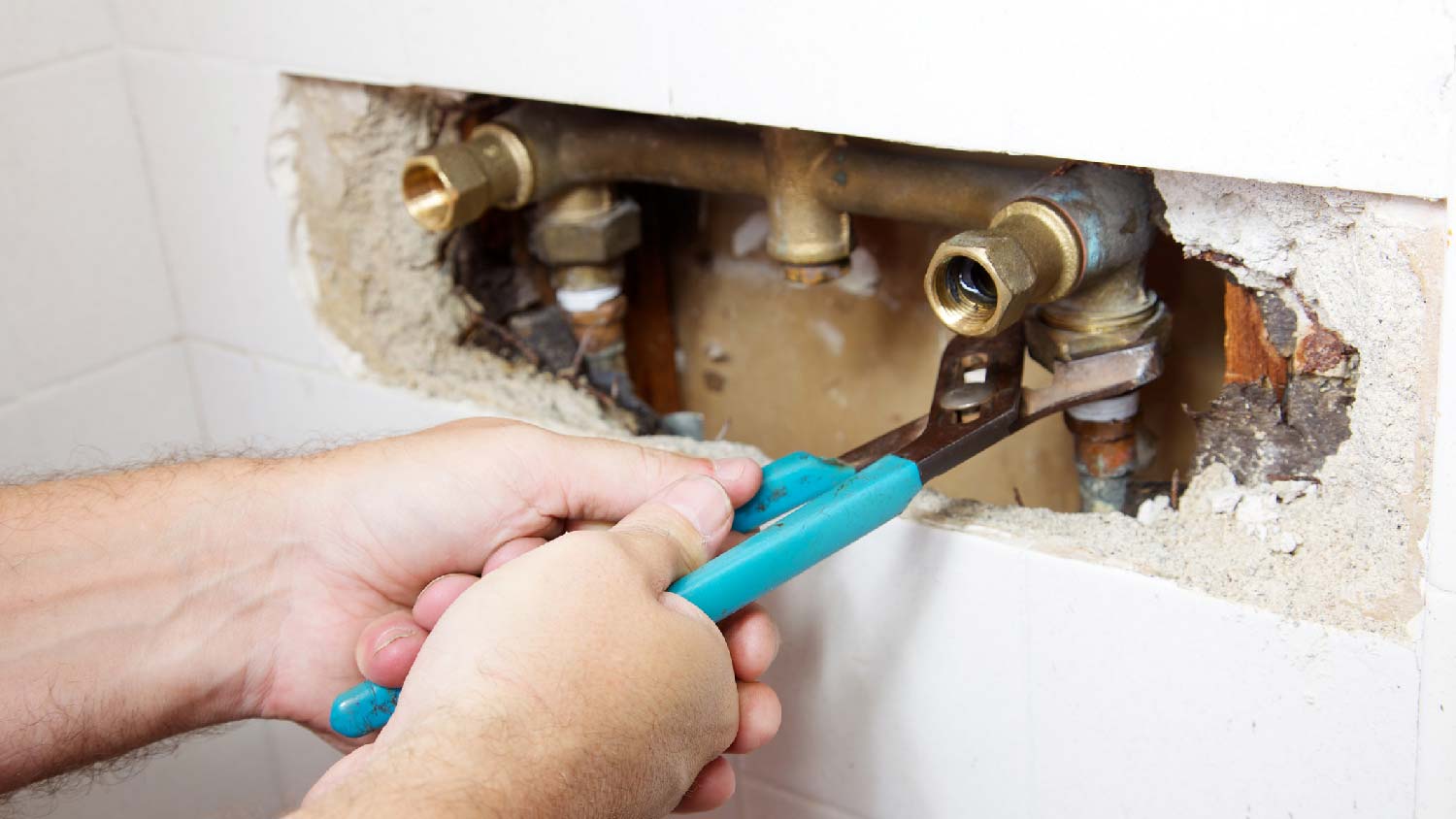 A person fixing a plumbing leak in the shower