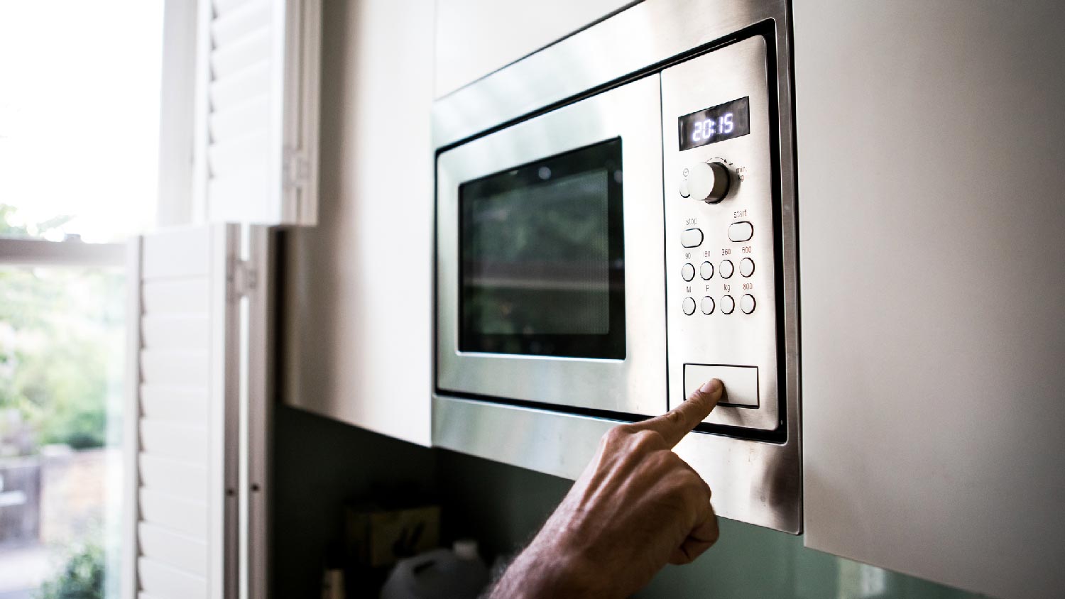 A person heating food in the microwave oven