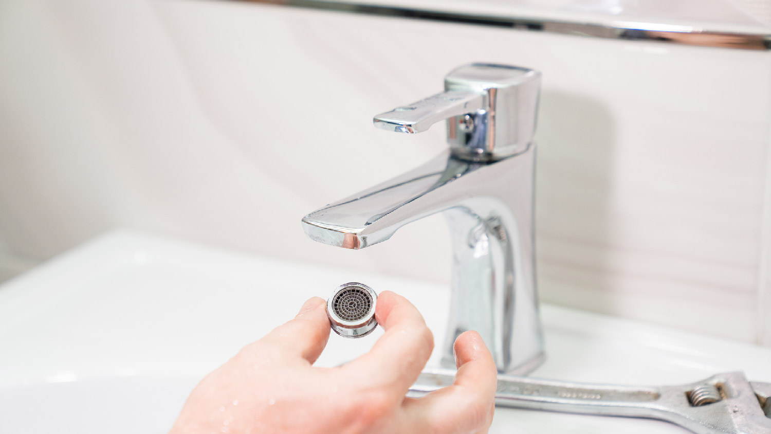 A person holding the aerator of a faucet