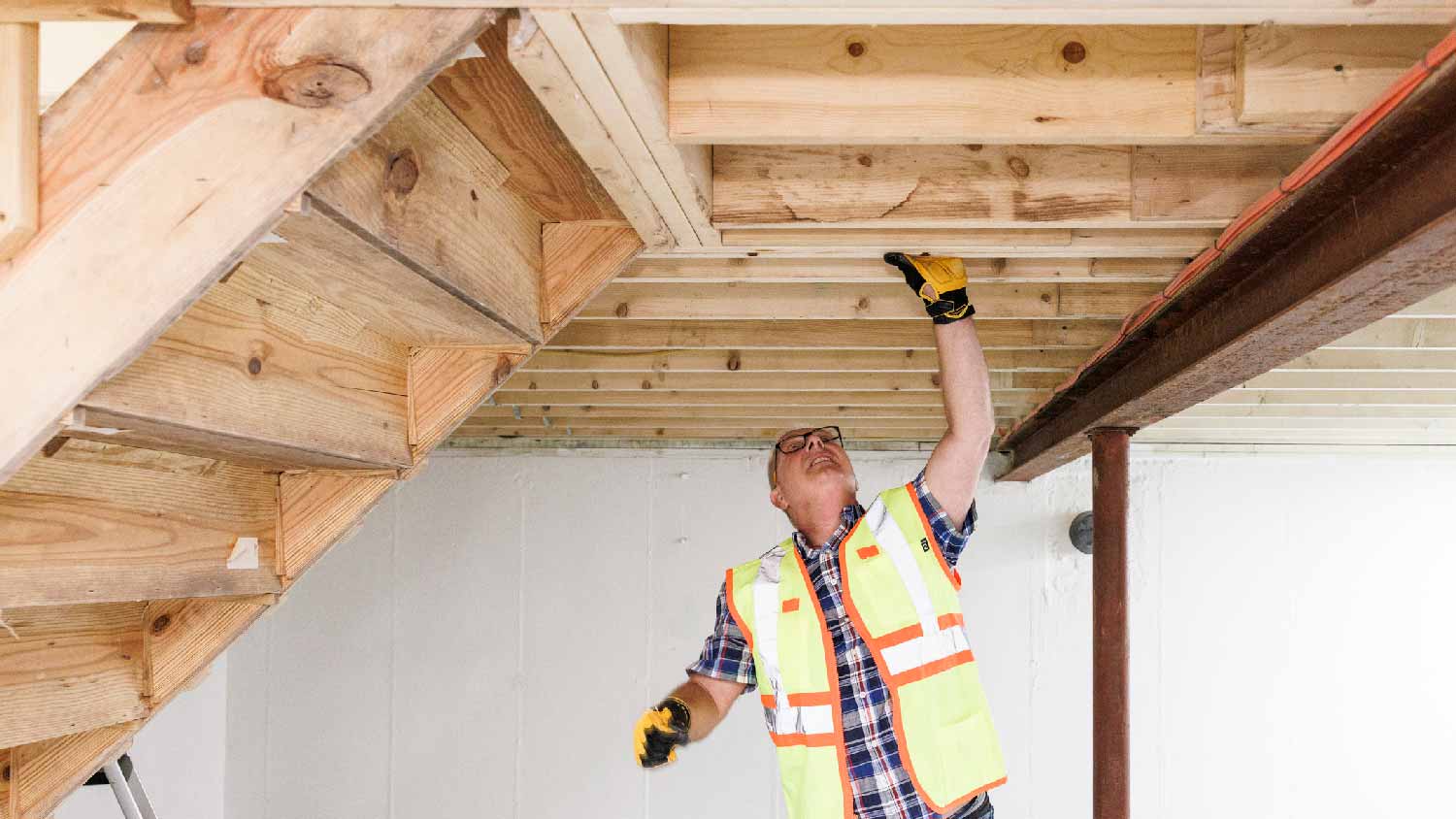 A person inspecting ceiling joists
