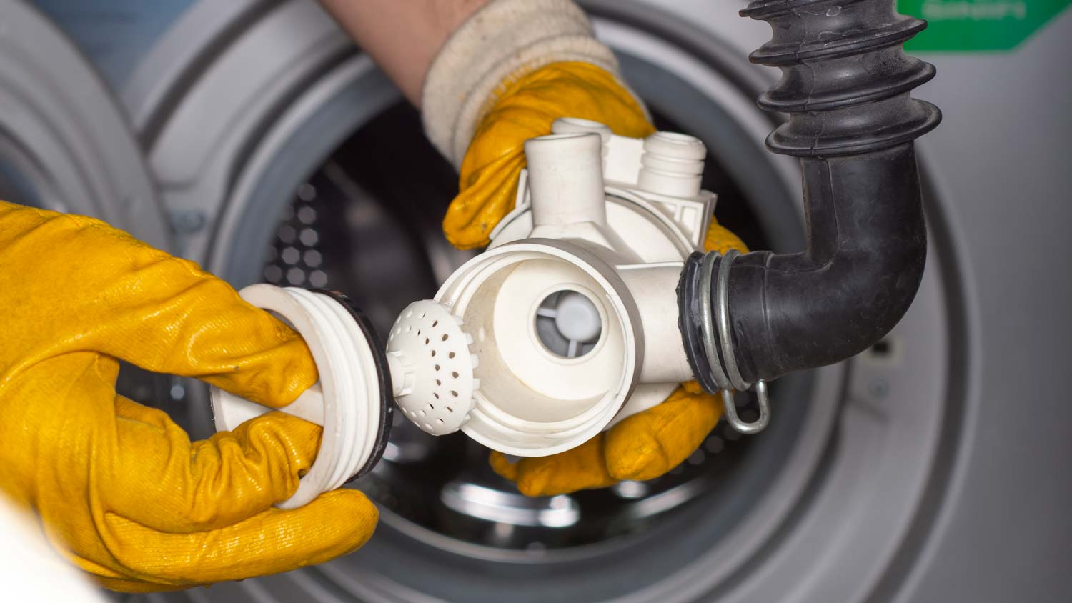 A person inspecting the drain pump of a washing machine