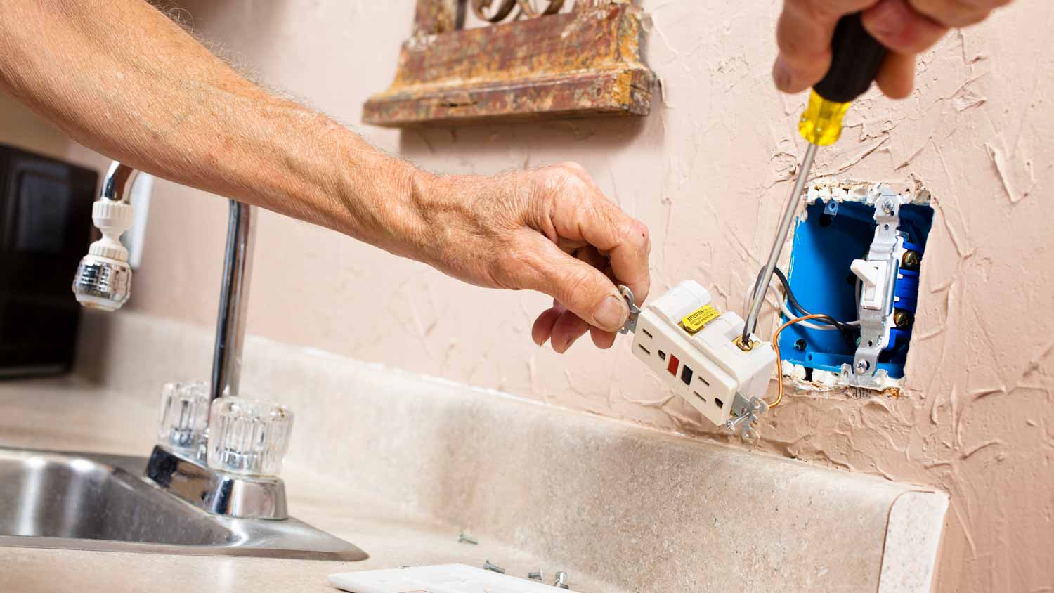 A person installing a GFCI outlet