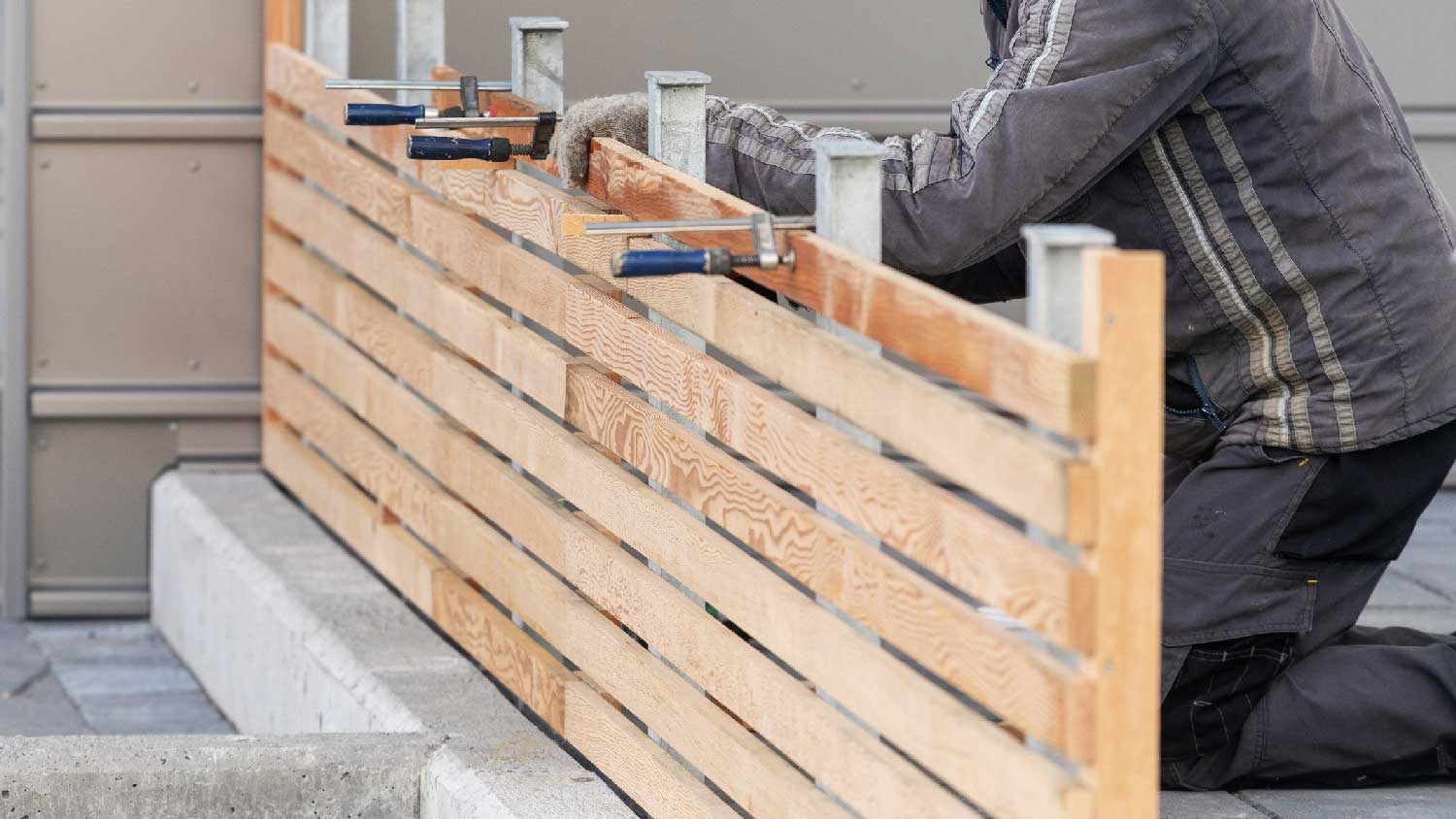 A man installing additional fence boards