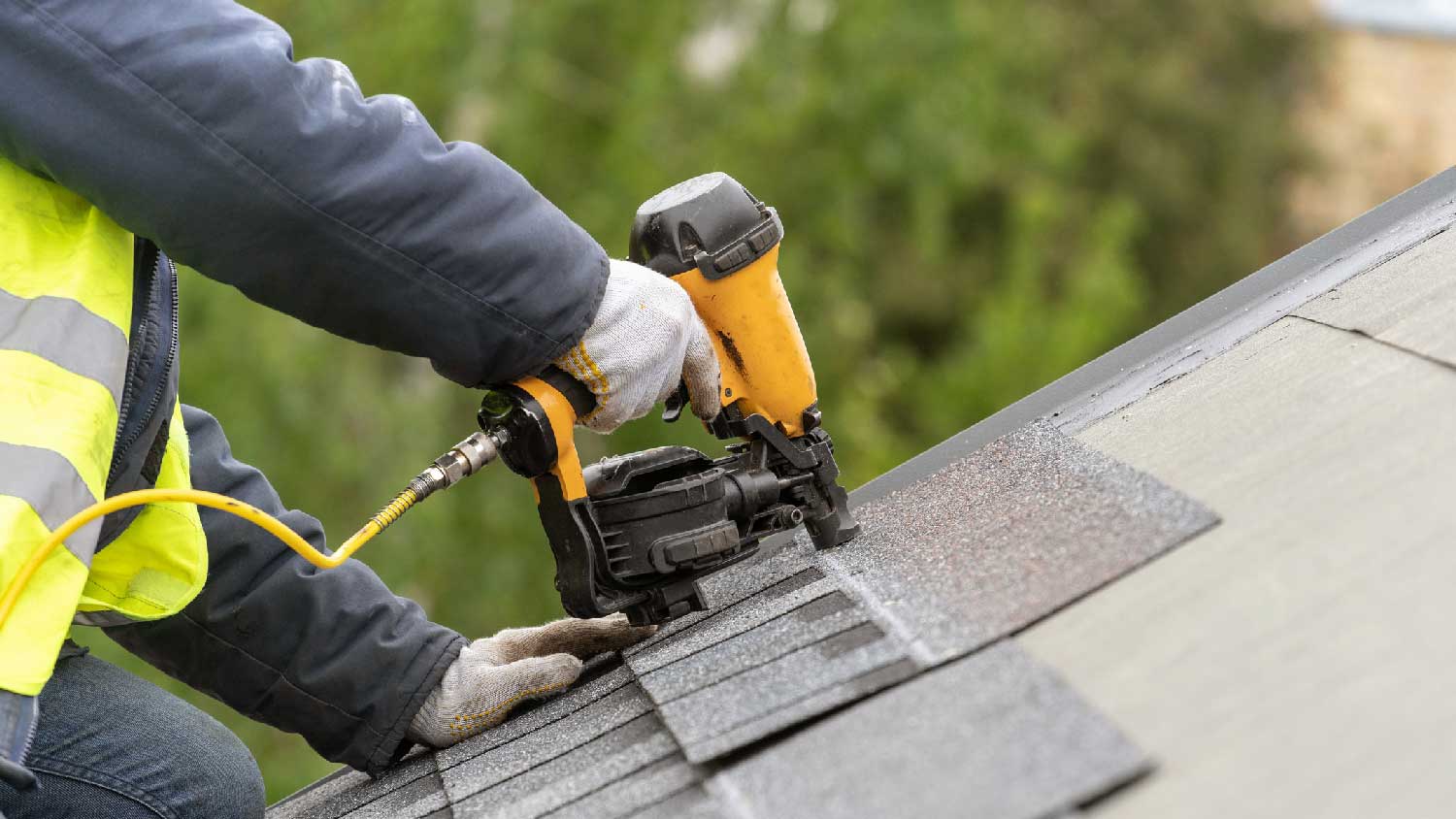 A person installing architectural shingles