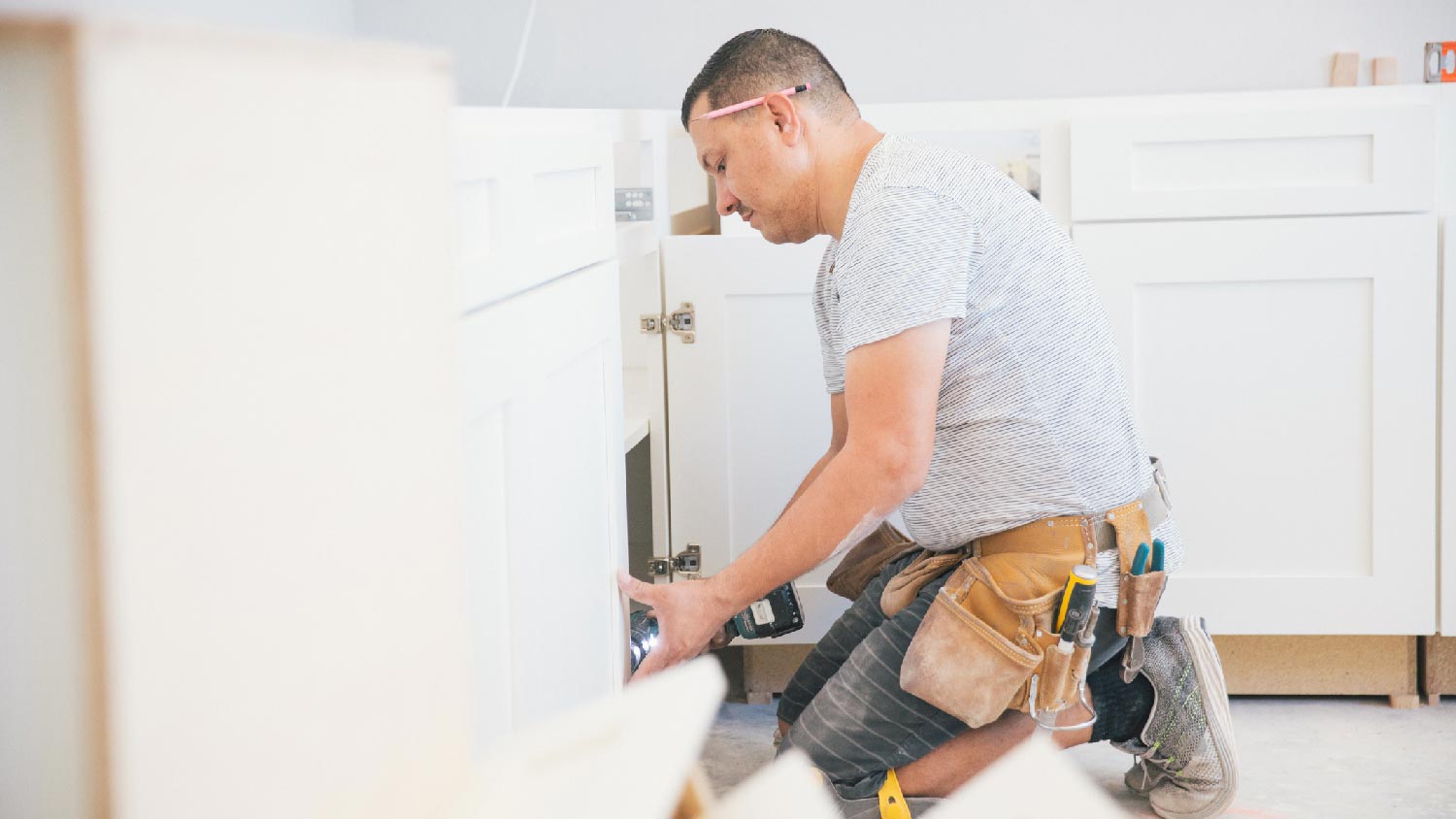 A person installing kitchen cabinets