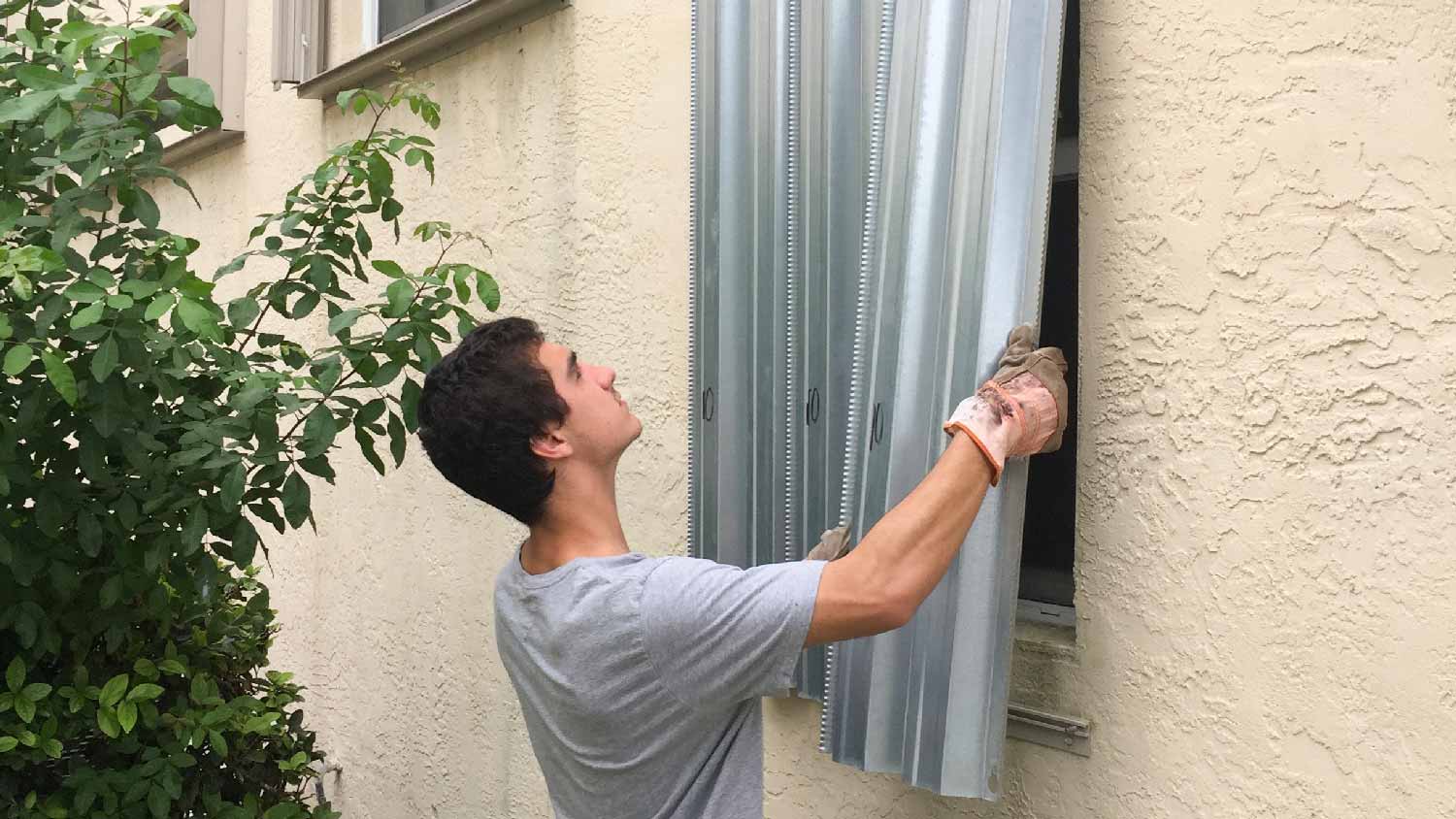 A person installing metal hurricane shutters