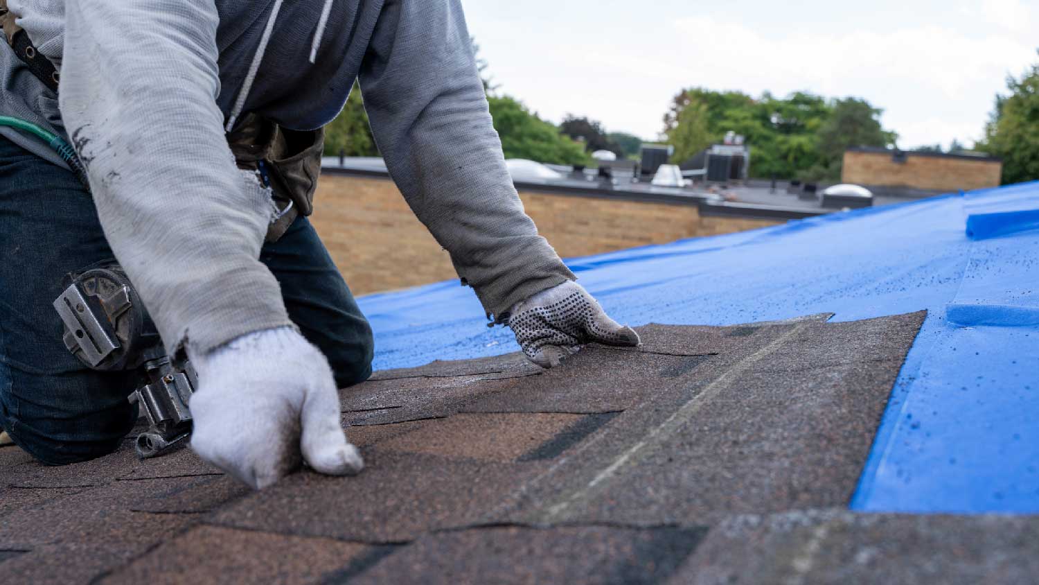 A person installing new asphalt shingles