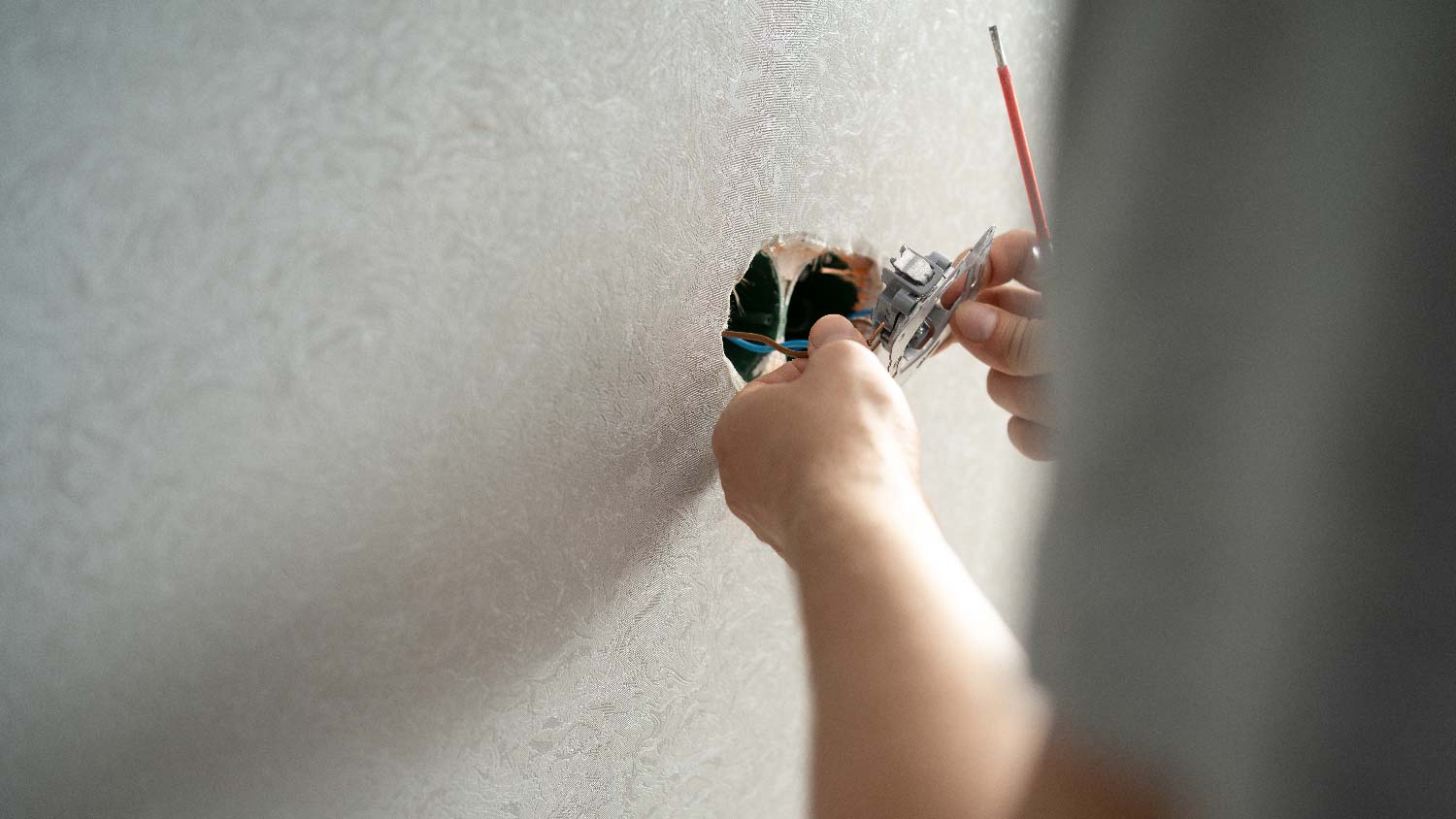 A person installing a new electrical outlet