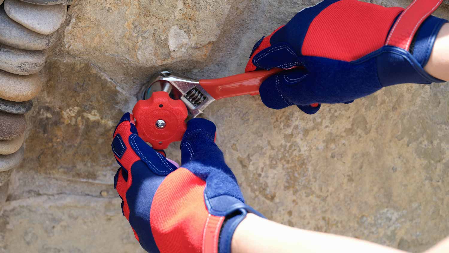 A person installing an outdoor spigot