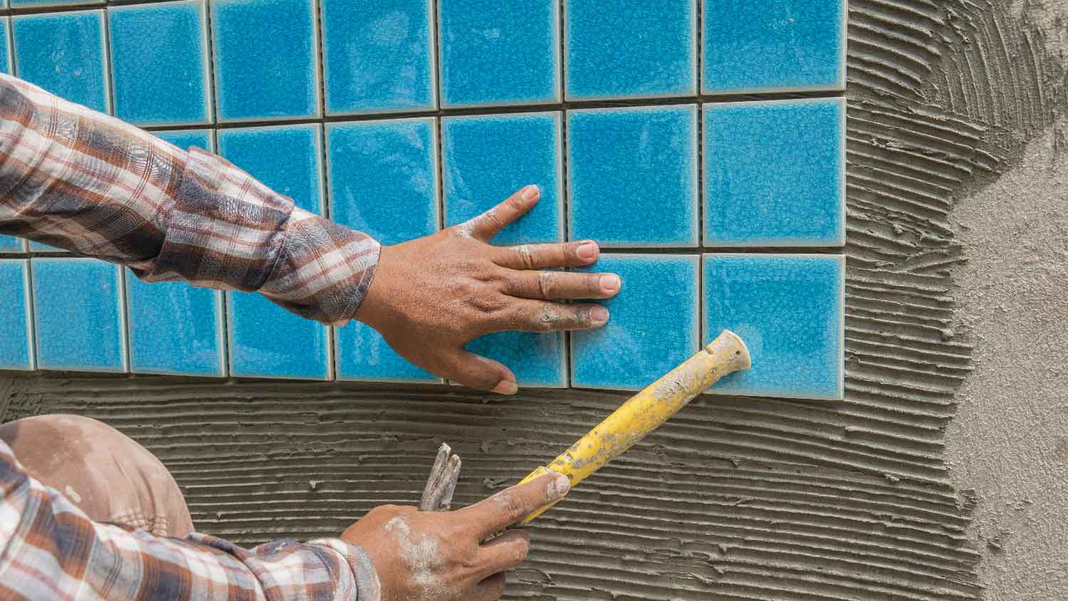 A person installing pool tiles