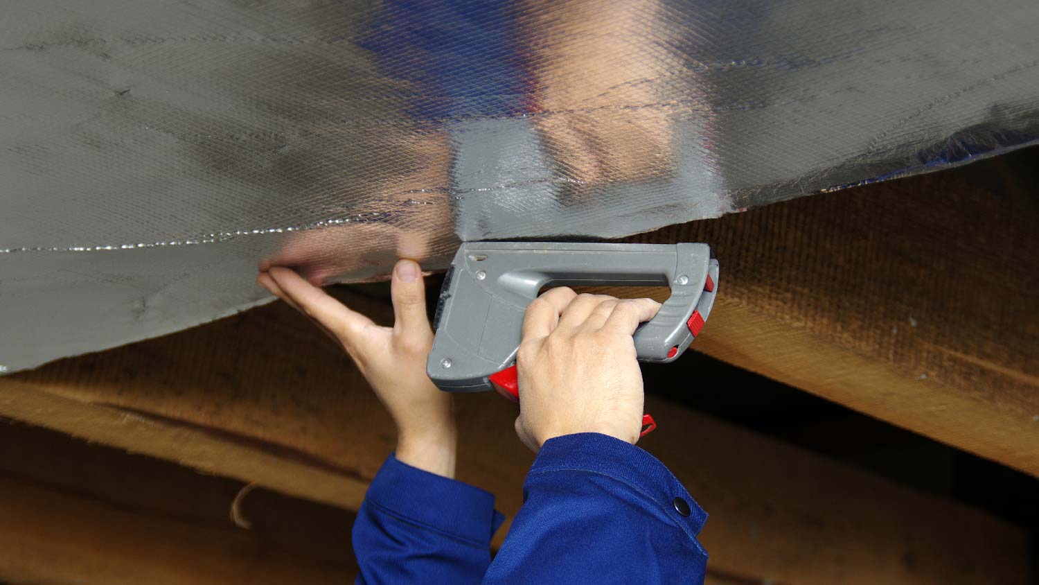 A person installing a radiant barrier