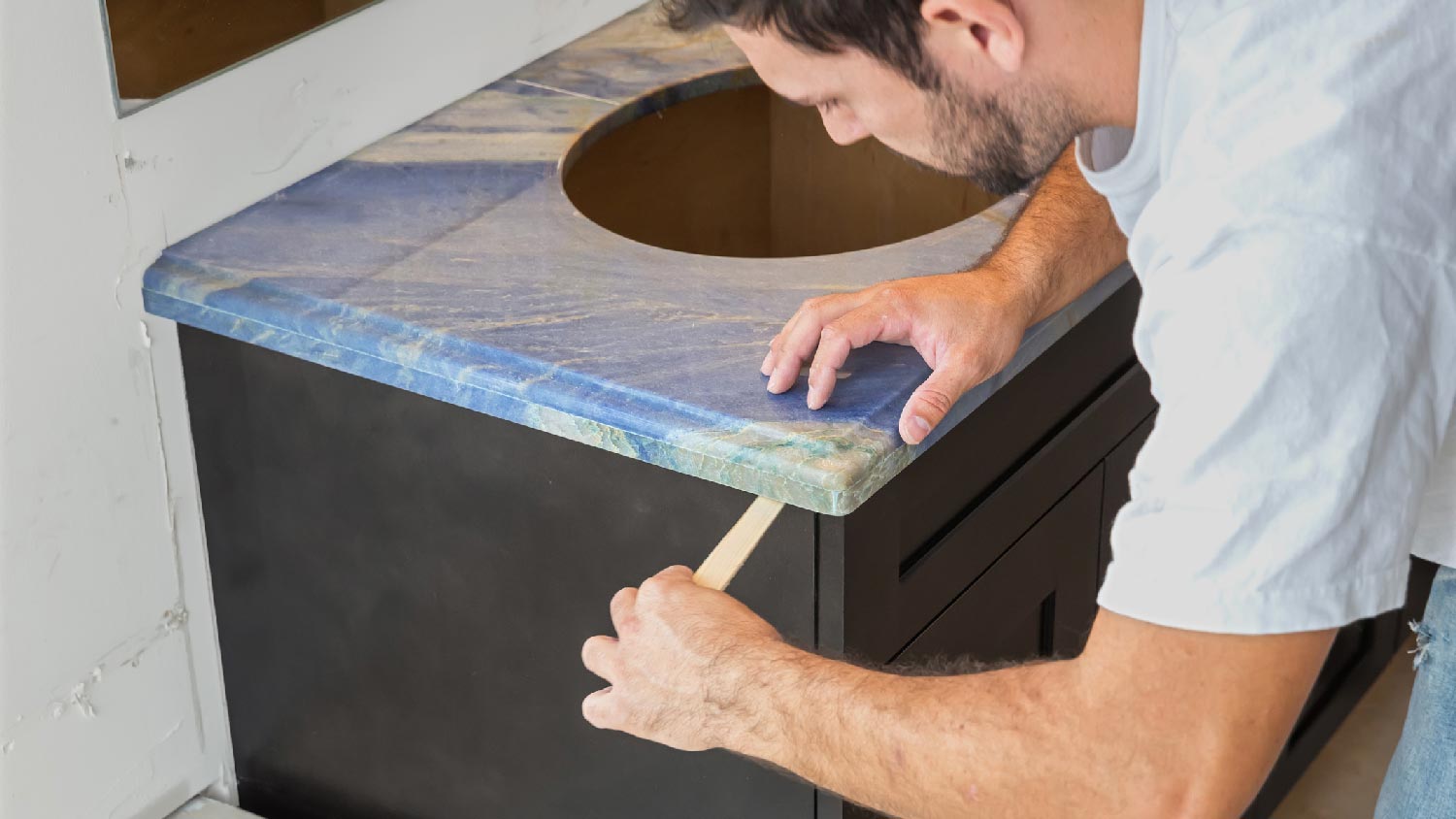 A person installing a sink to a bathroom vanity