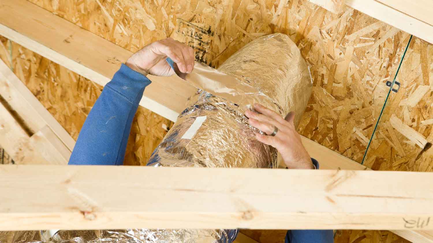 A person insulating an air duct