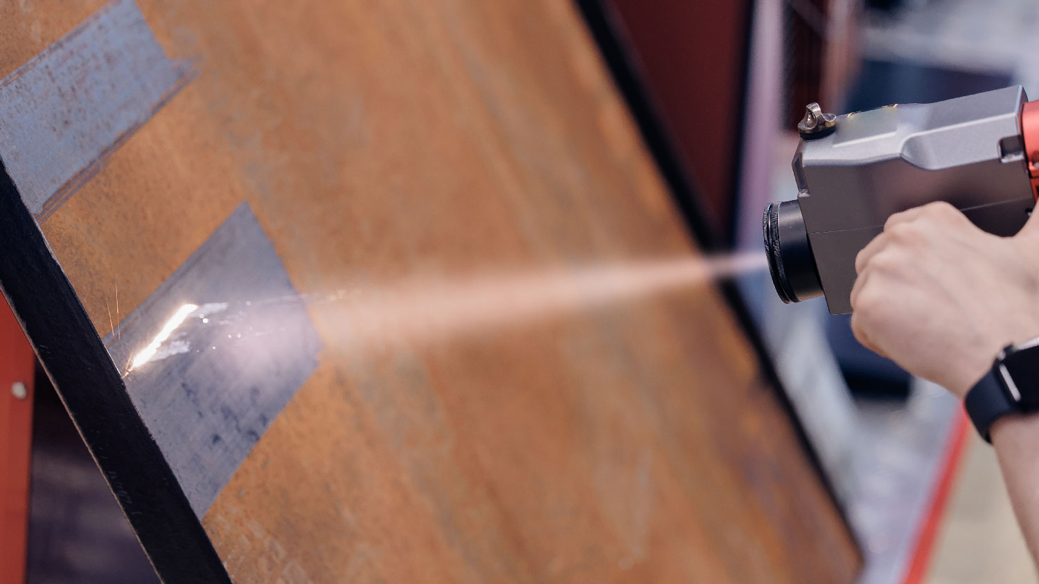 A person laser cleaning a metal surface