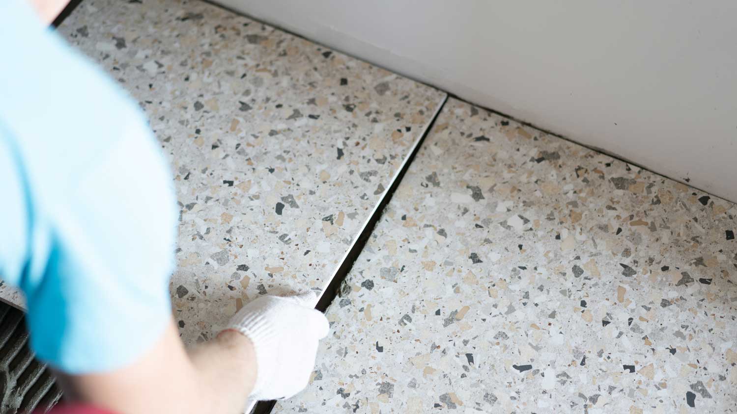 A person laying porcelain tiles on the floor