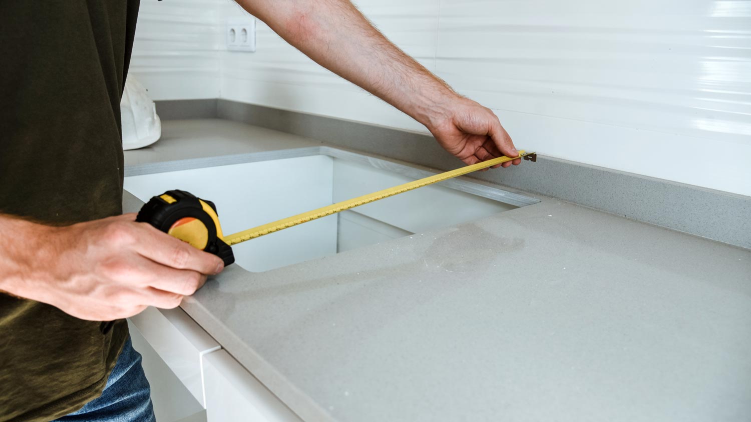 A person measuring a countertop for an undermount sink