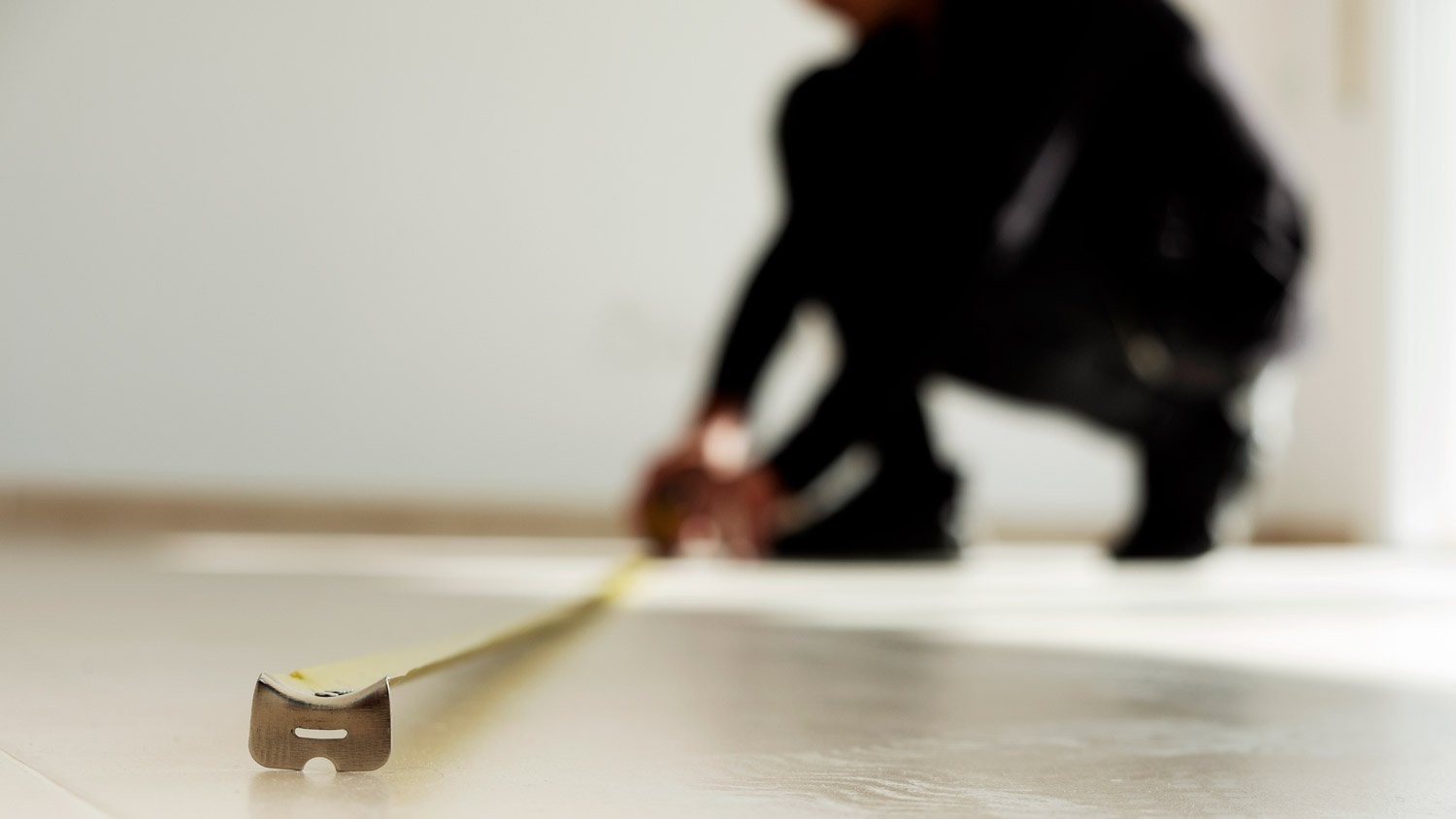 A person measuring the square footage of a room