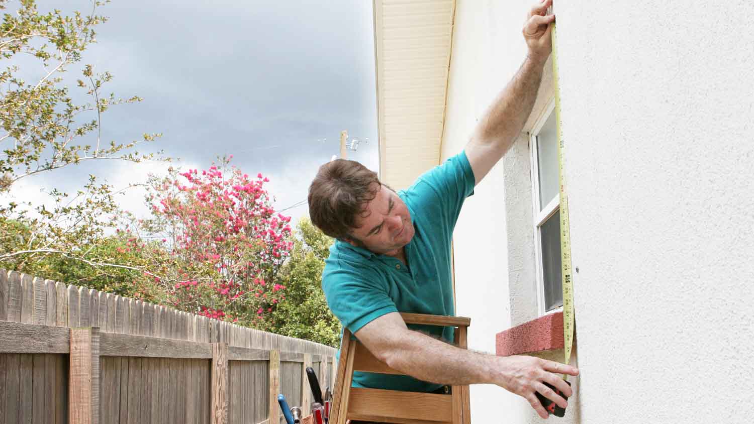 A person measuring to install a storm window