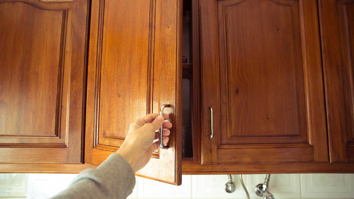 A person opening a face frame cabinet