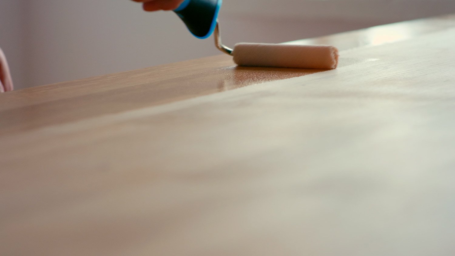 A person painting with a roller a corian countertop