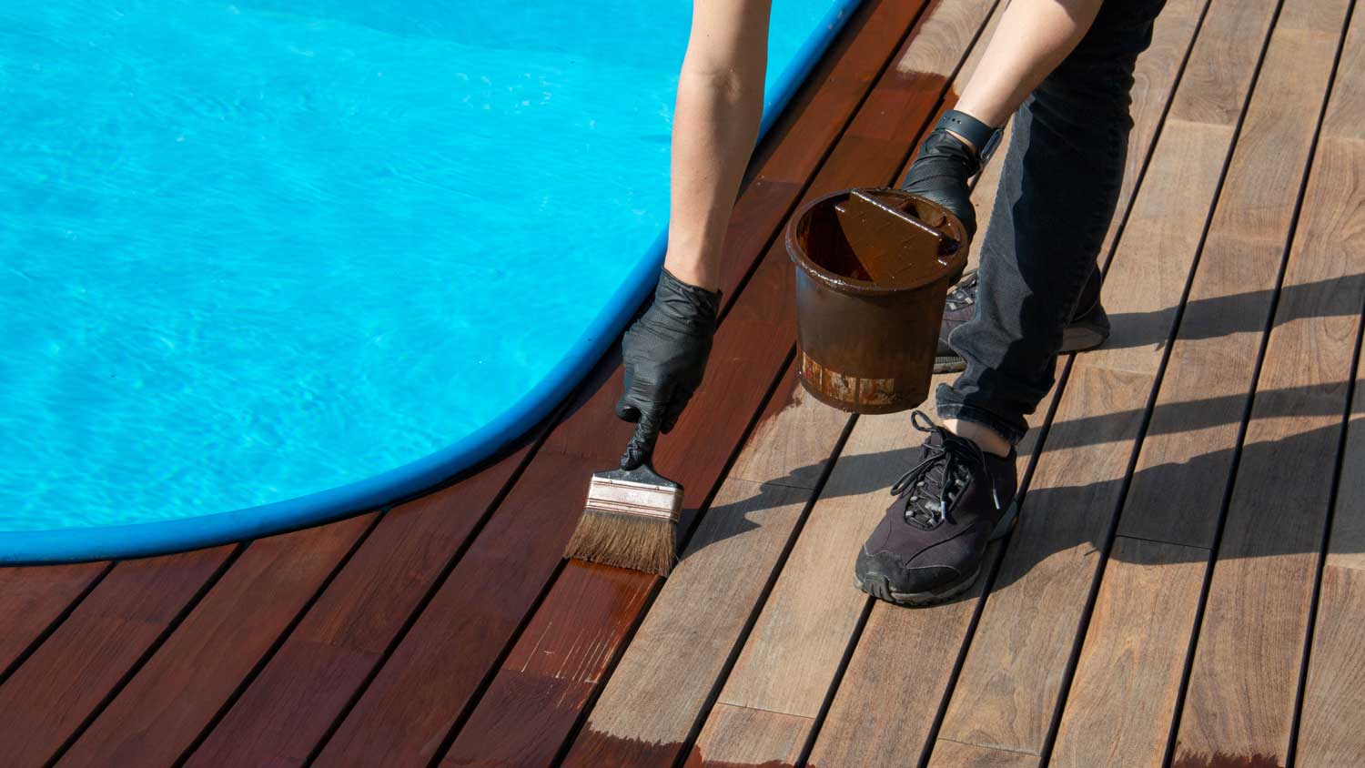 A person painting a wooden pool deck