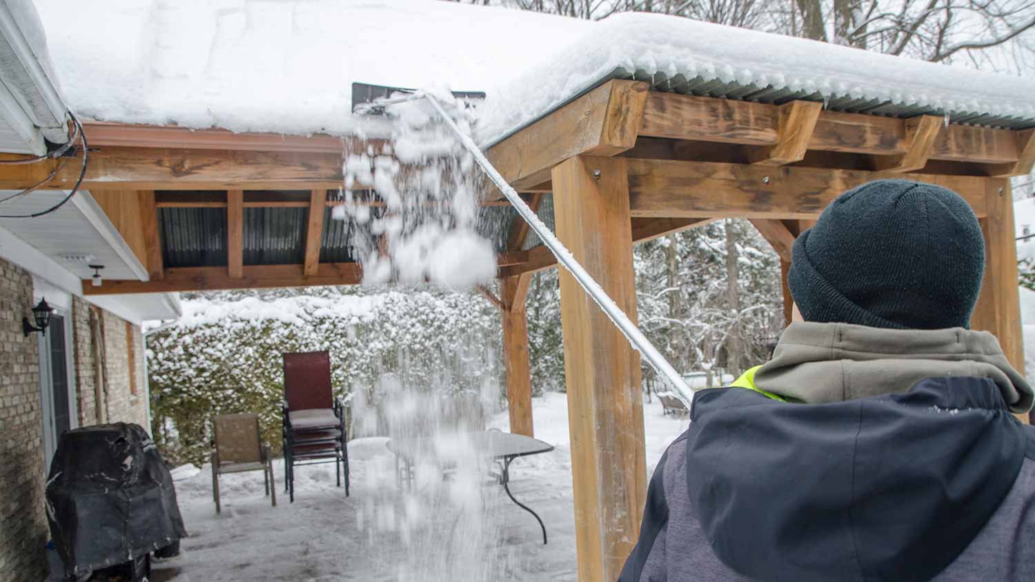 A person raking snow from a roof