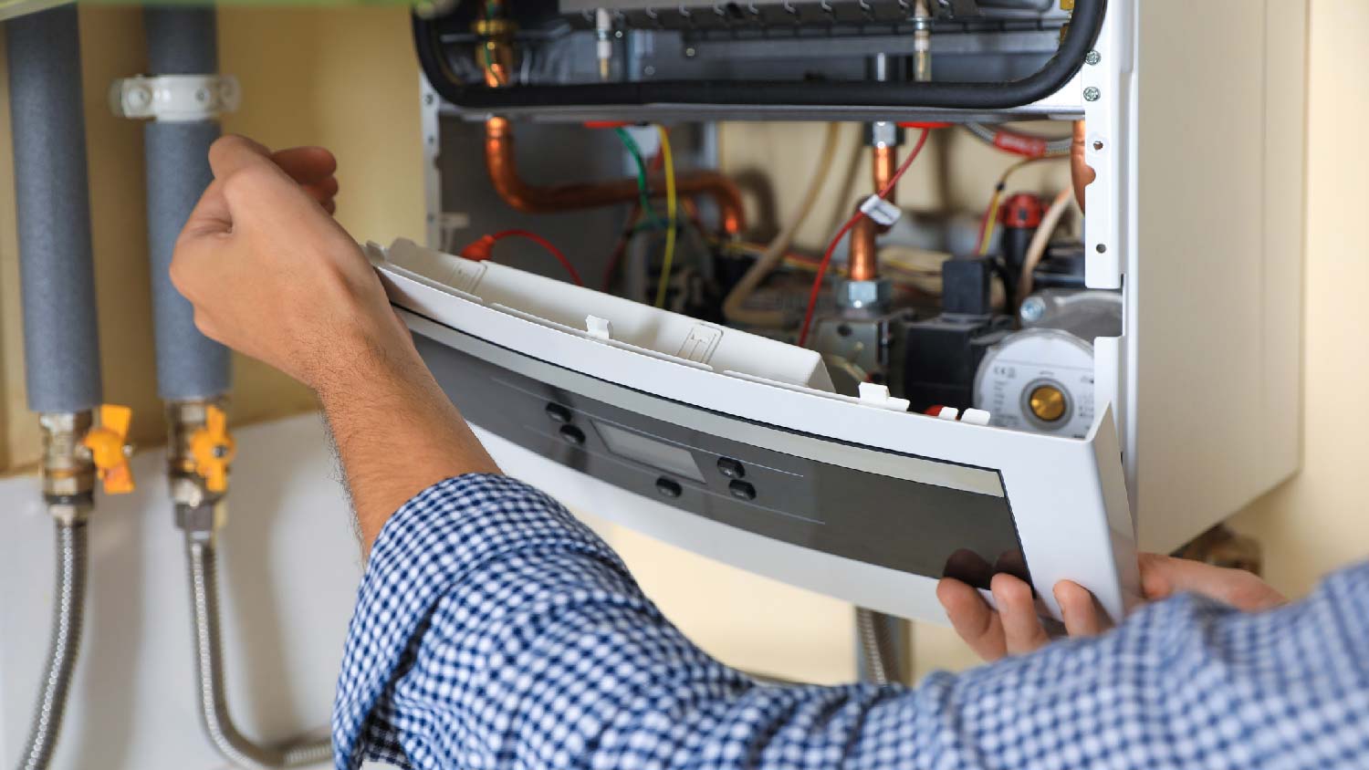 A person removing the front panel of a gas water heater 