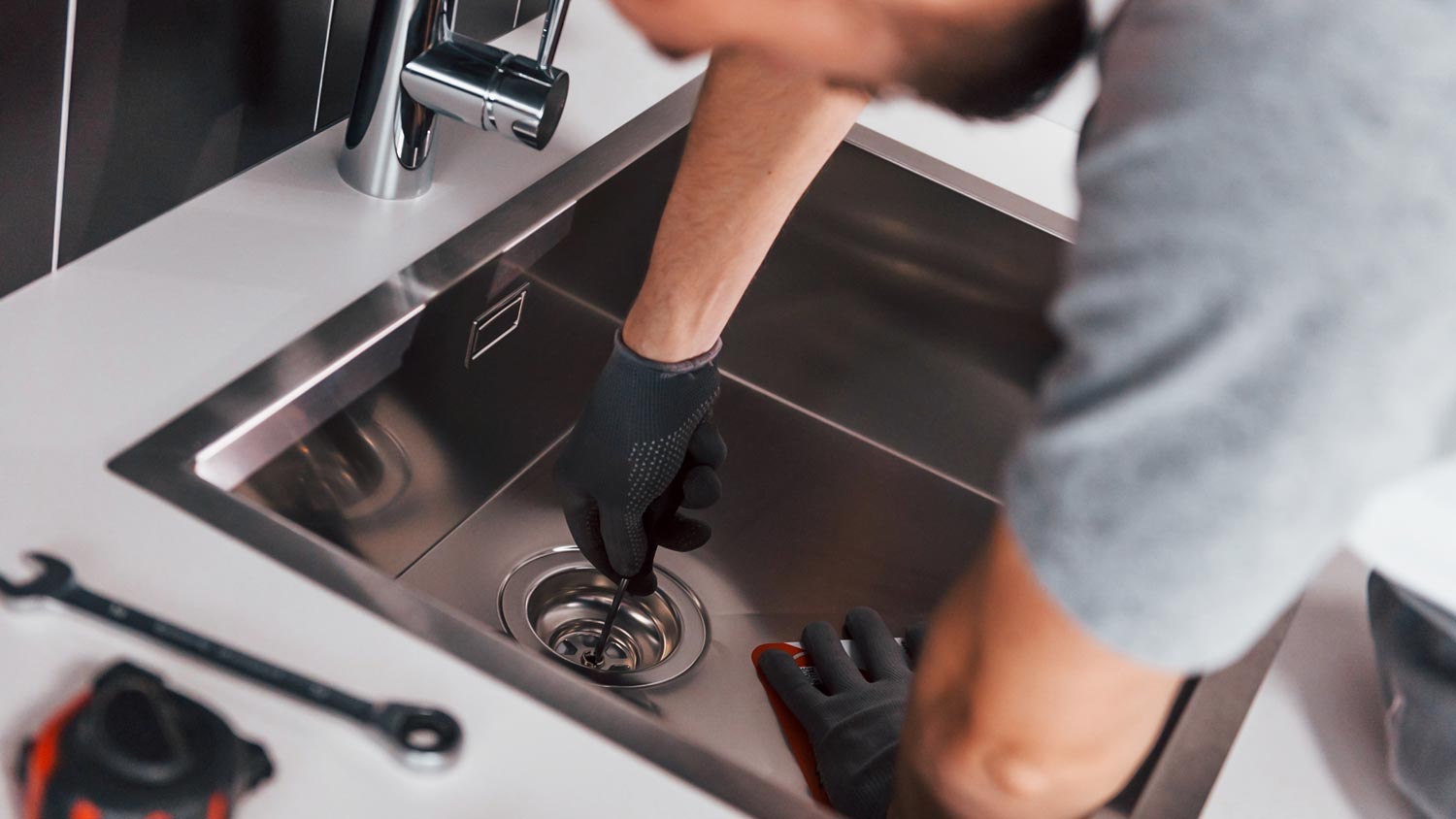 A person removing the garbage disposal from a sink