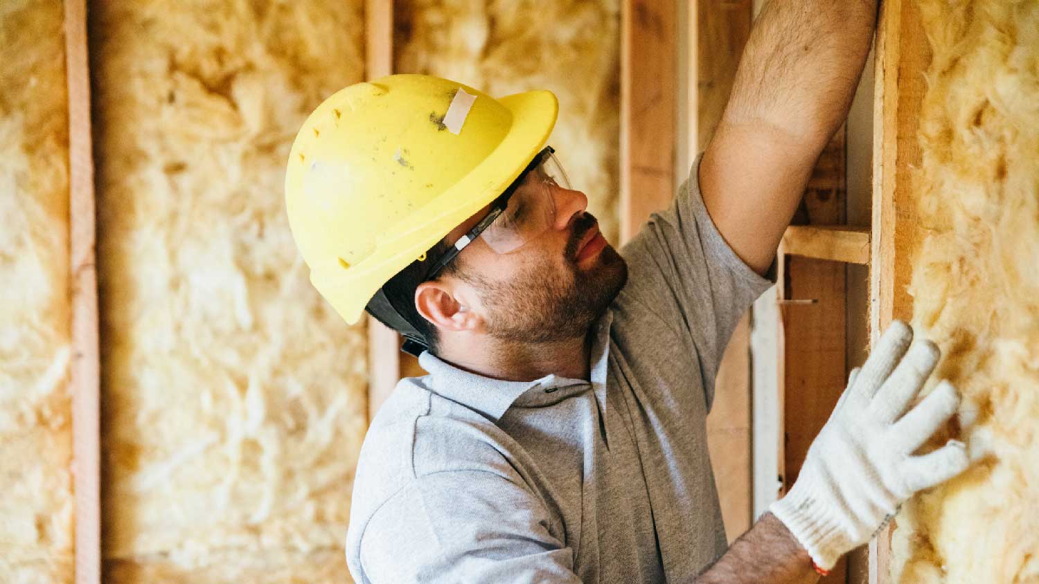 A person removing the insulation from an attic