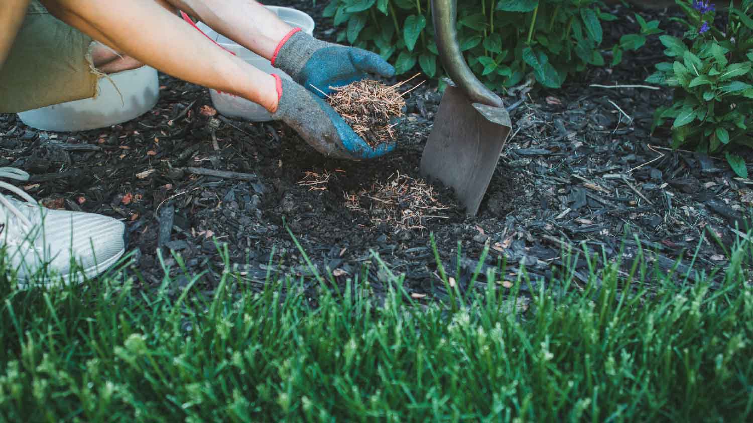 A person removing mulch by hand