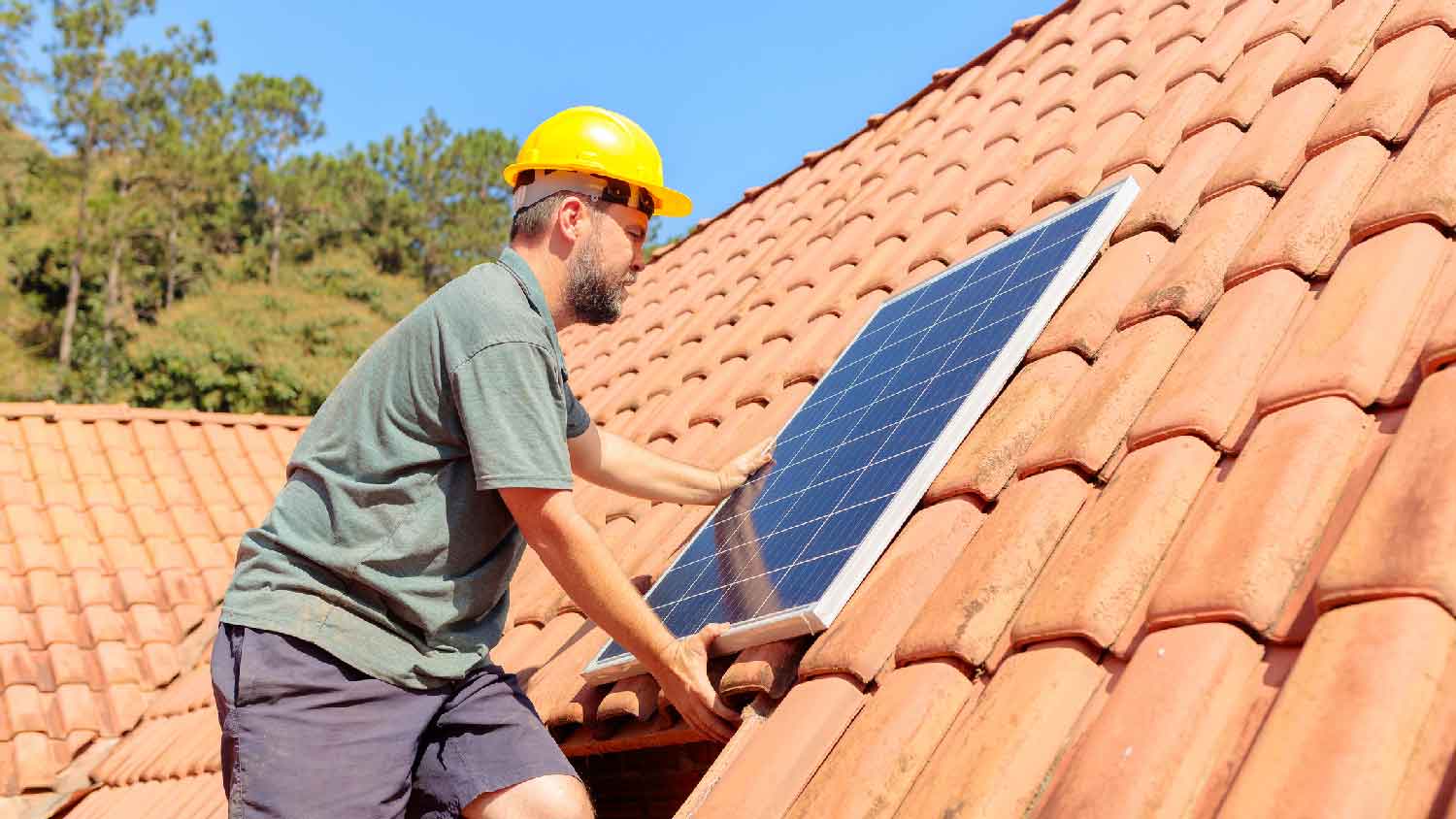 A person removing a solar panel from the roof