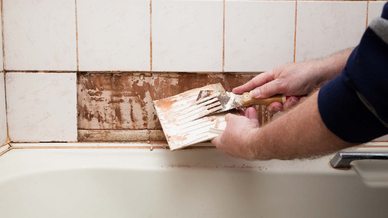 A person removing tiles in order to remove an old bathtub