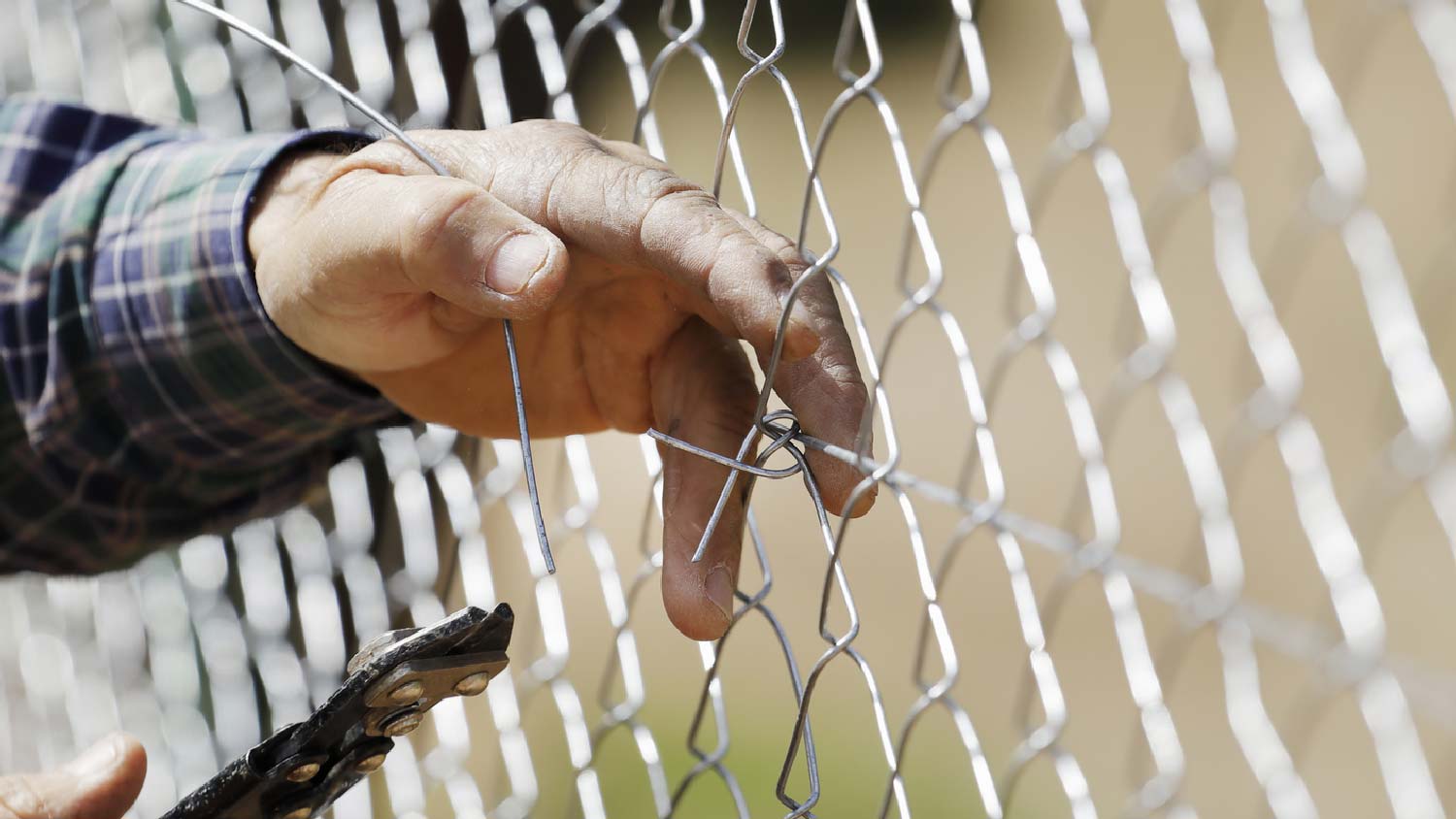 A person repairing a chain link fence