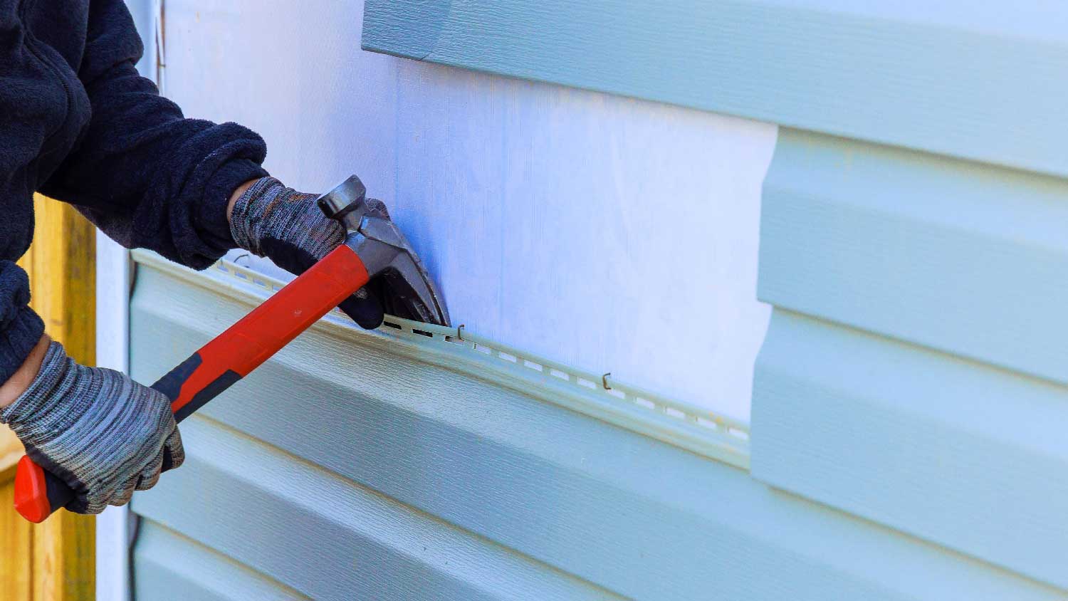 A person repairing a house siding