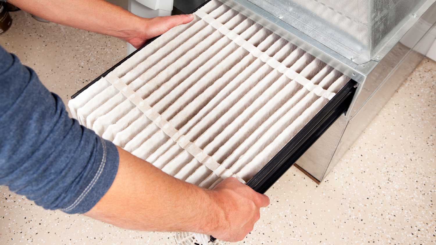 A person replacing the furnace filter