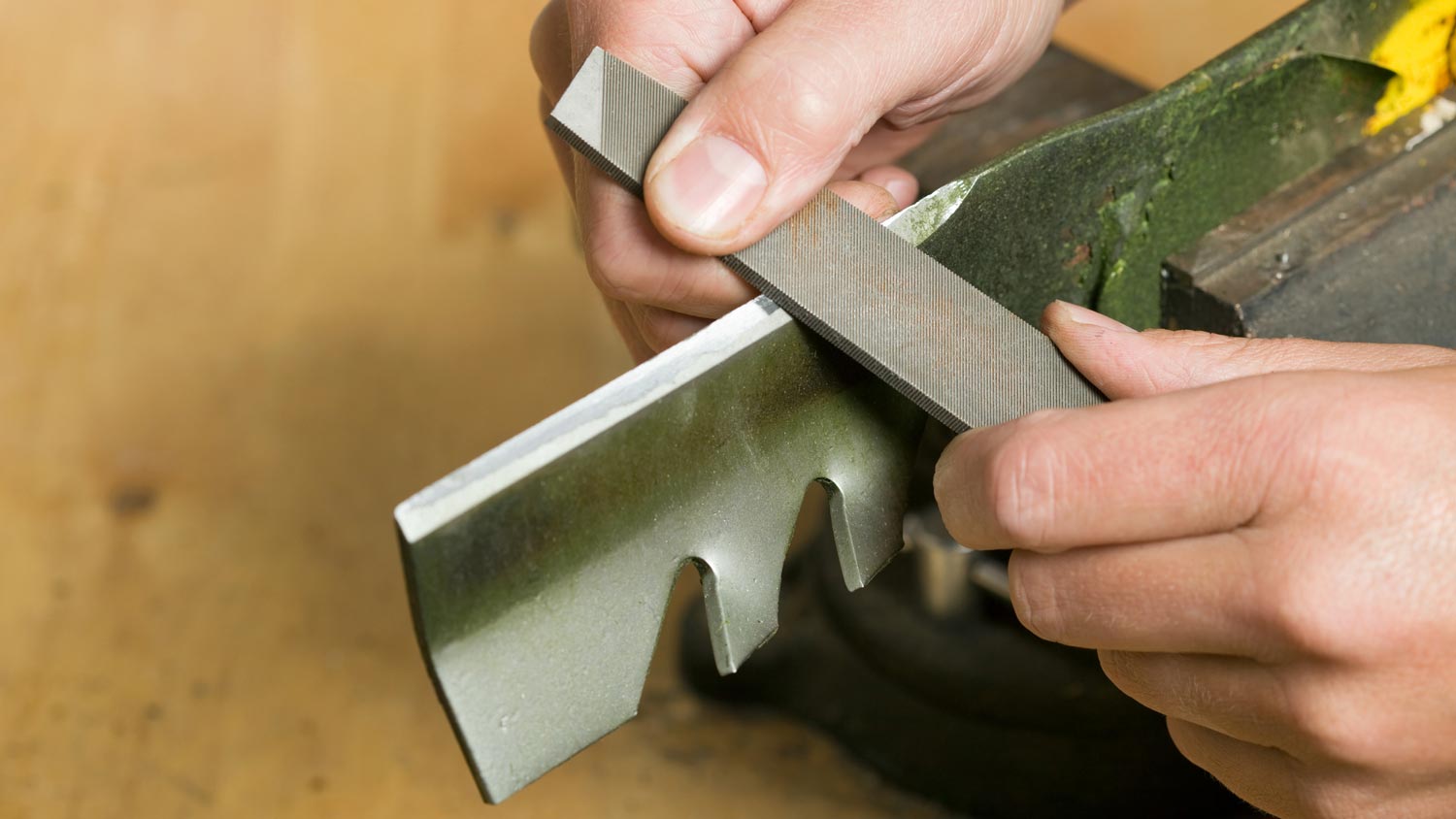 A person sharpening mower blades