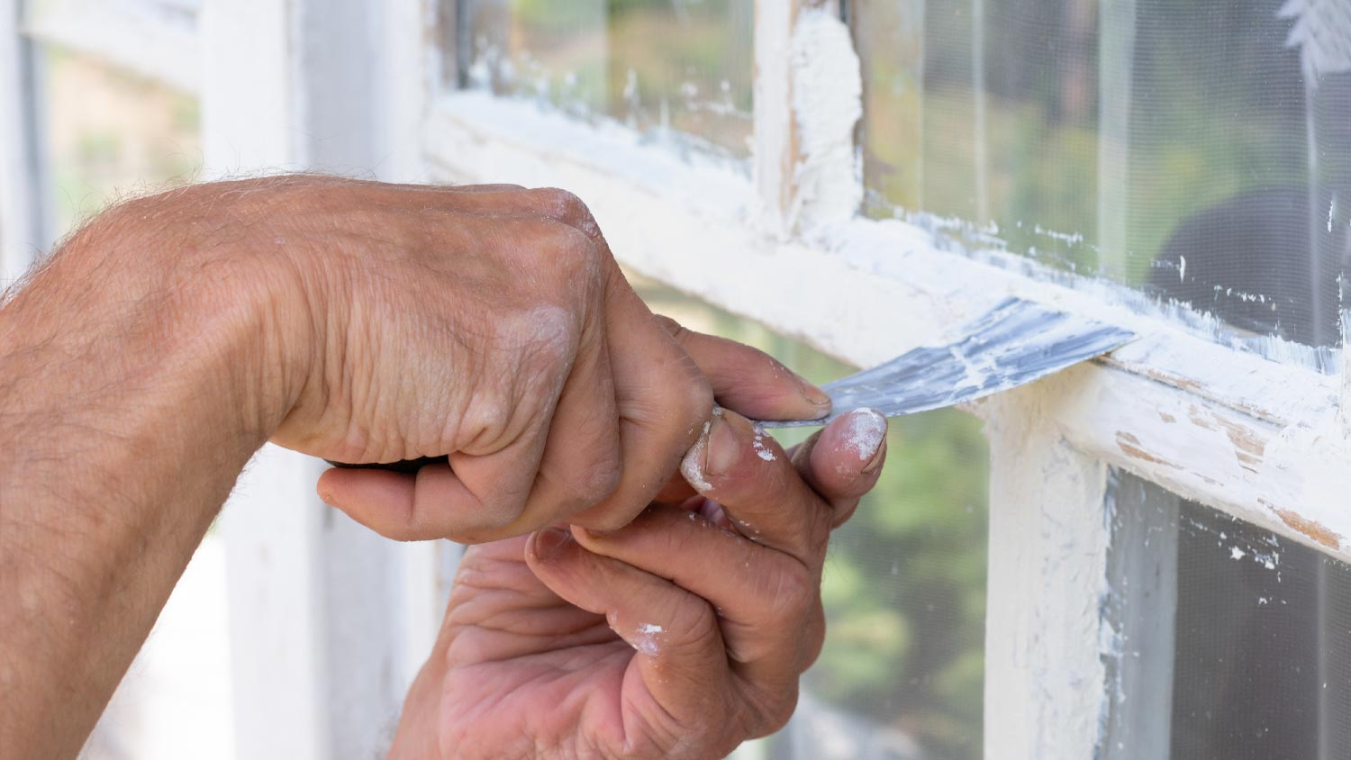 A person smoothing a glazing compound 
