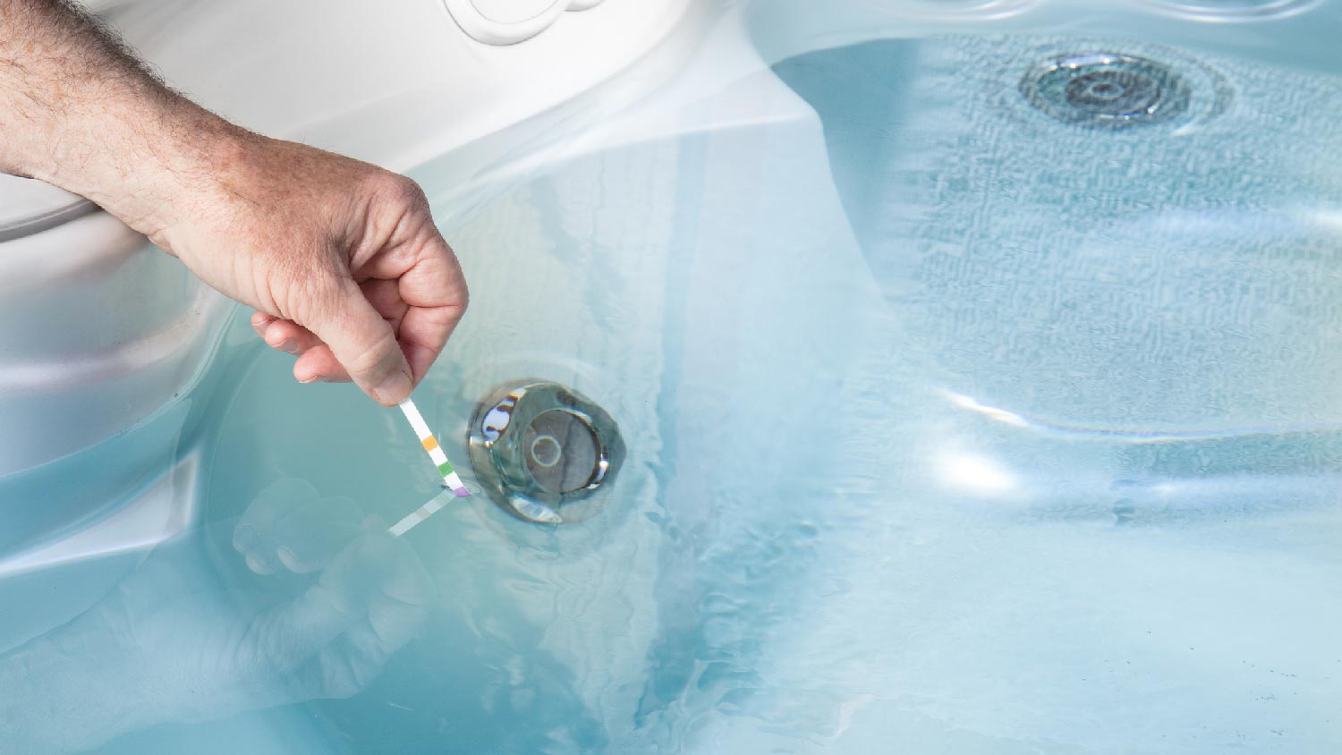 A person testing pH levels of a hot tub