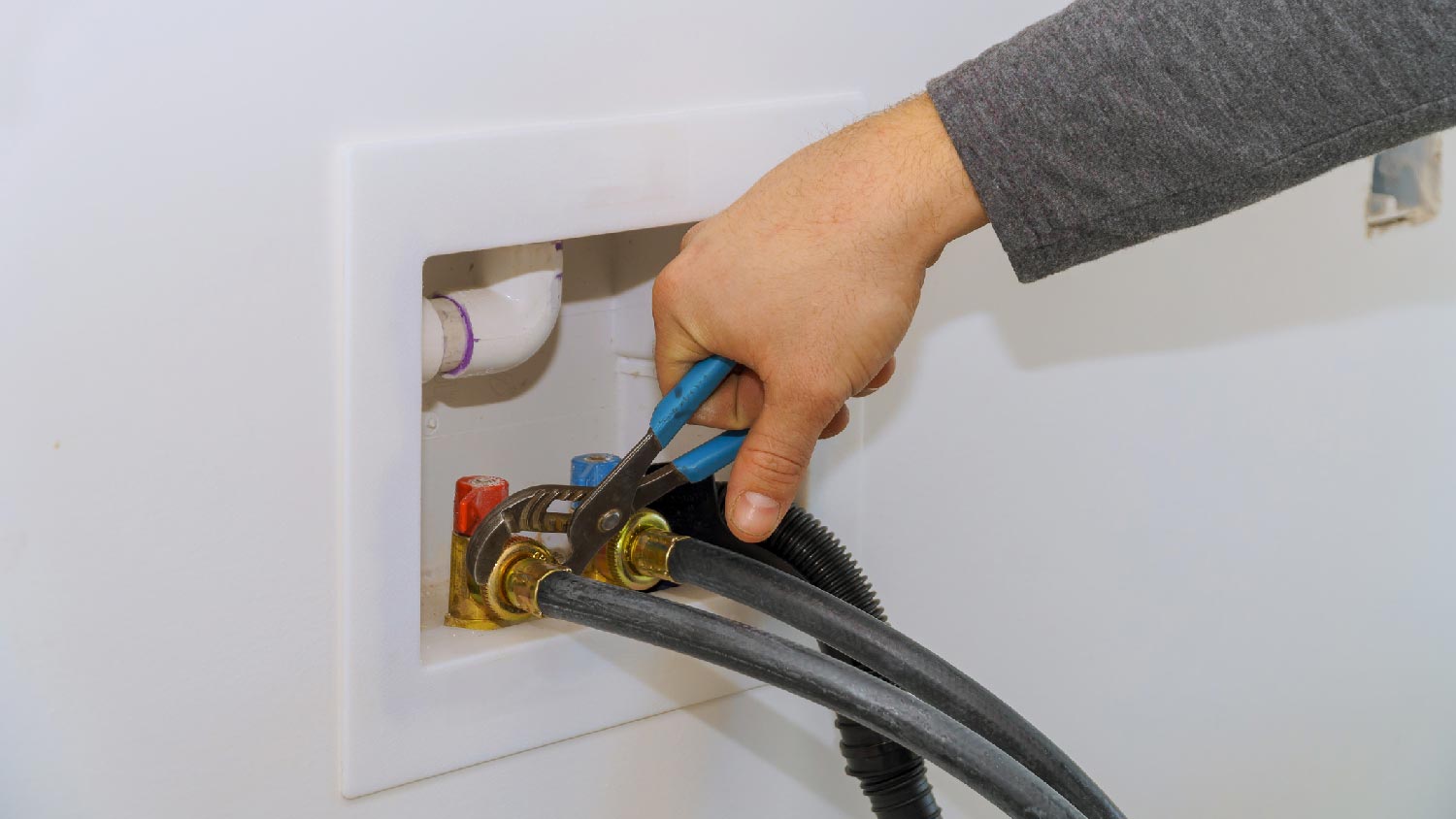 A person tightening pipes of a washing machine