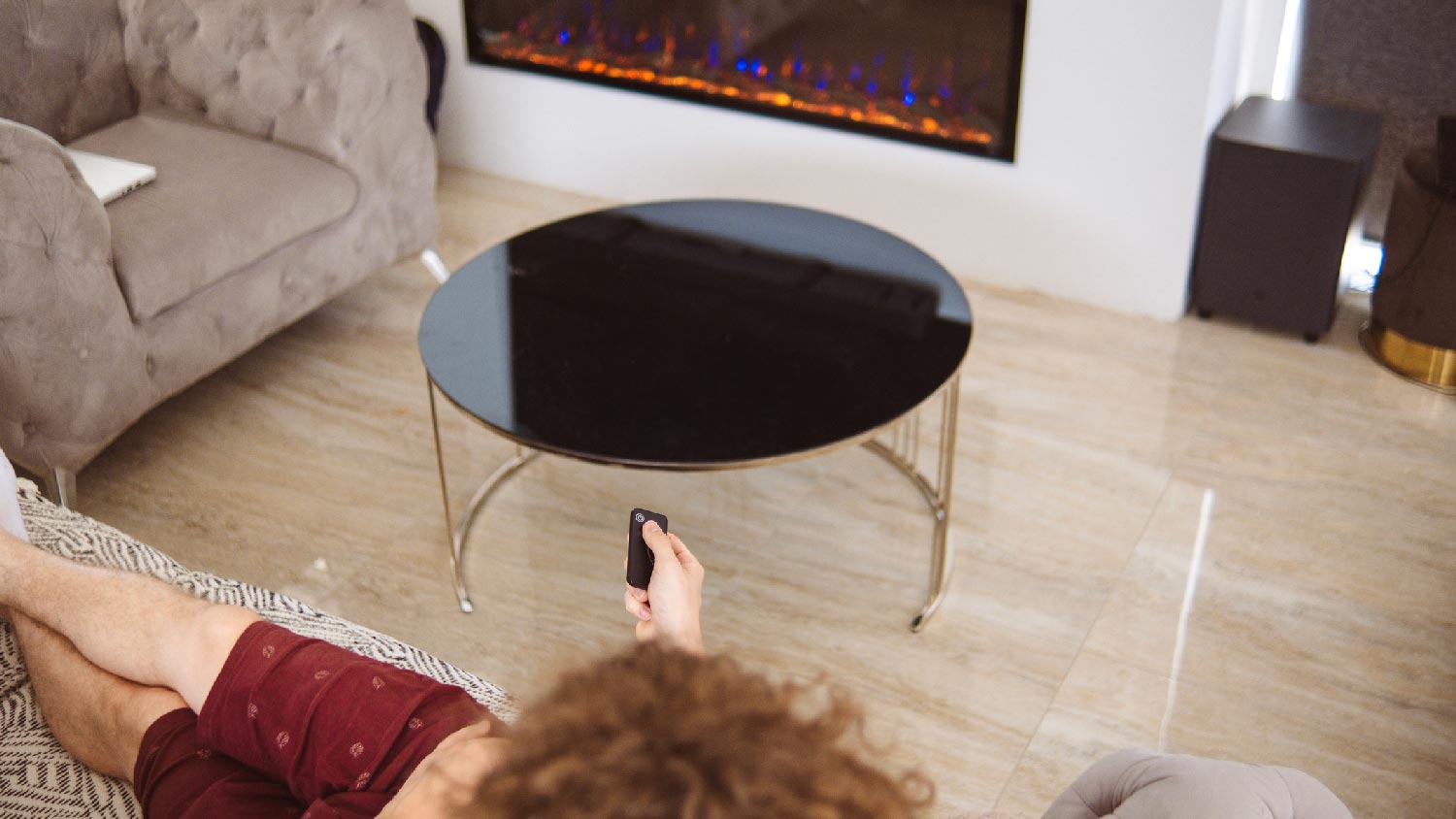 A person turning off a fireplace via a remote control