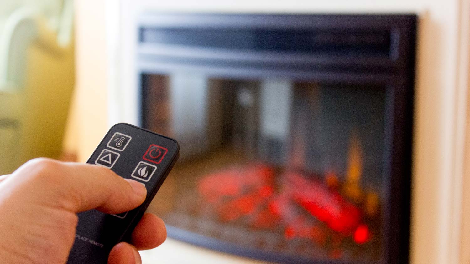 A person turning off an electric fireplace via a remote control