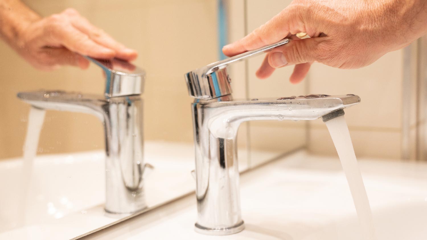 A person turning on a faucet by lifting the handle