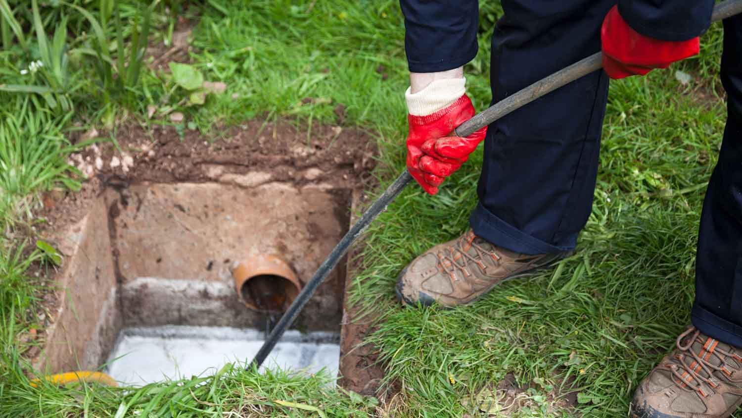 A person unclogging a main sewer line