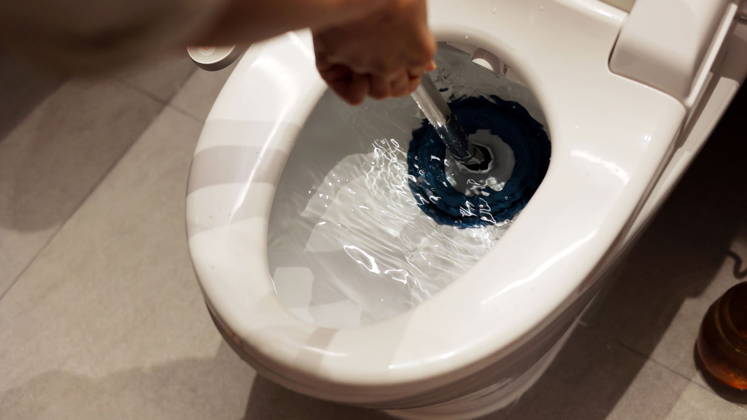 A person using a plunger in a toilet