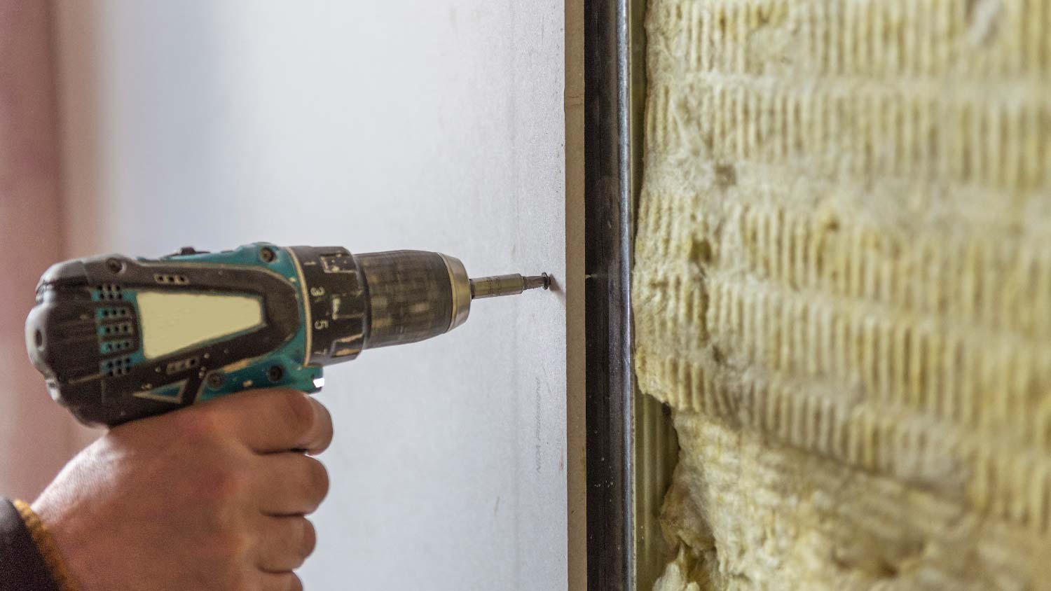 A person using screws on drywall